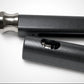 Close-up of a black cylindrical object with a metallic tip on a white background, featuring a logo in the corner.