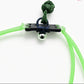 Green slingshot with a black anchor and silver ball on a white background, featuring a brand logo in the corner.